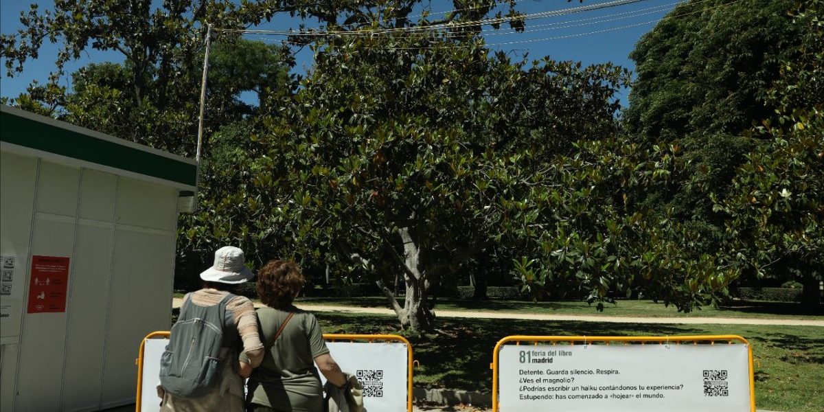 Dos visitantes observan la rama de un magnolio de la Feria del Libro de Madrid